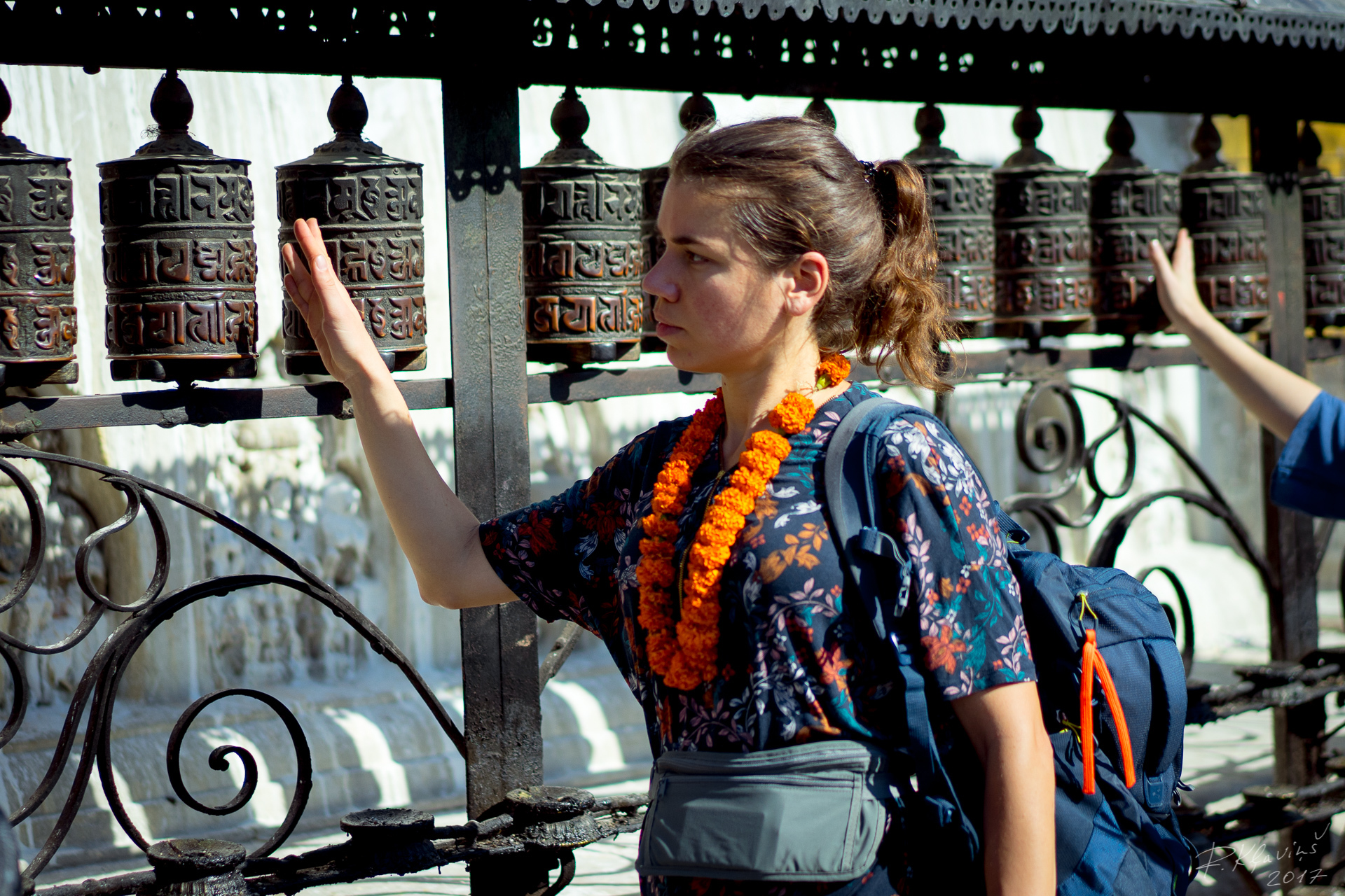 Een vrouw met een rugzak die naar gebedsmolens kijkt.