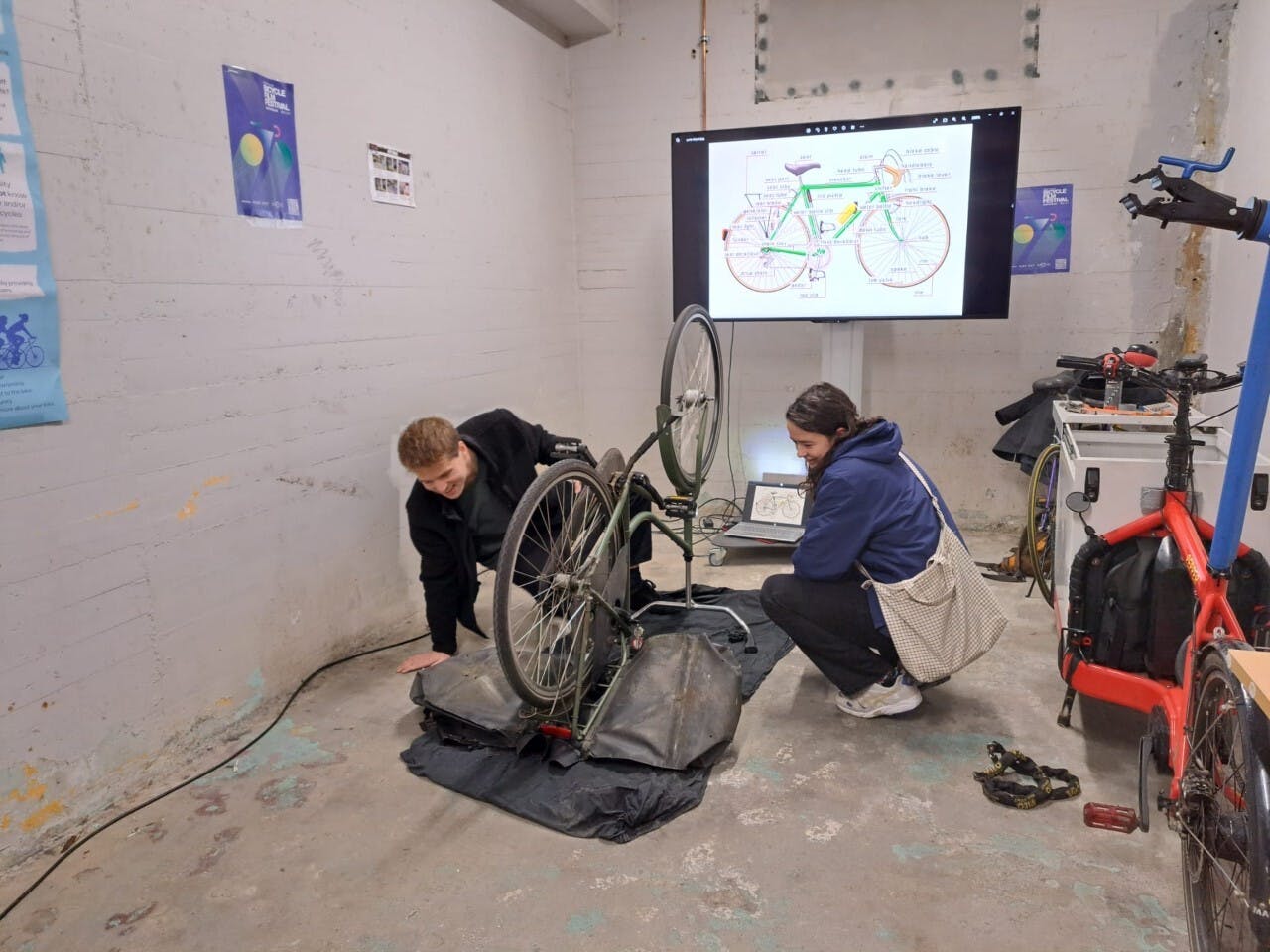Fietsenmaker en student sleutelen aan een fiets in de Bike Kitchen