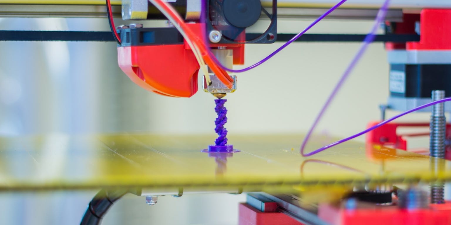 Een 3D-printer met een paarse draad eraan.