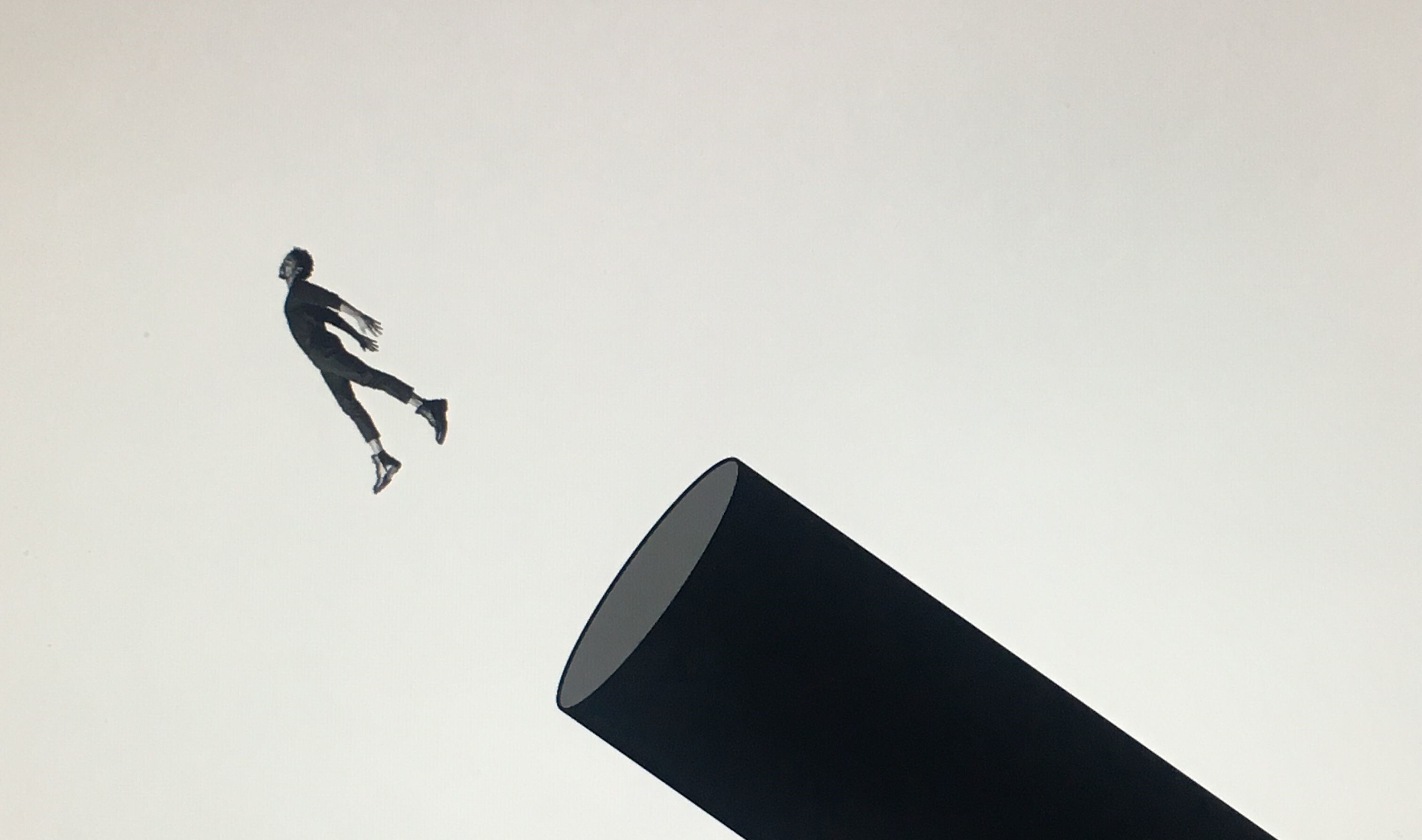 Een silhouet van een man die uit een ronde koker springt.