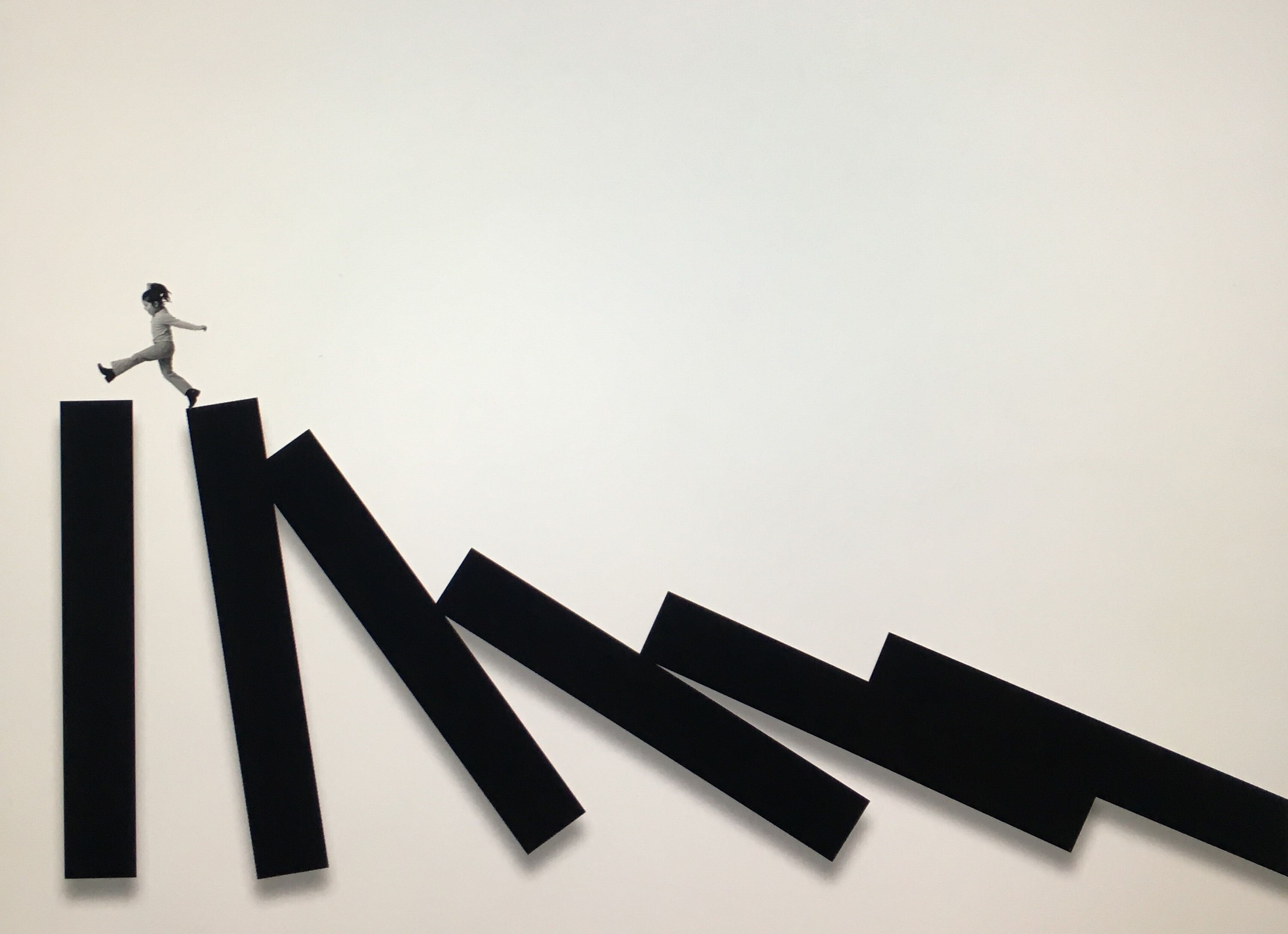 Een man rent over een reeks omvallende dominostenen